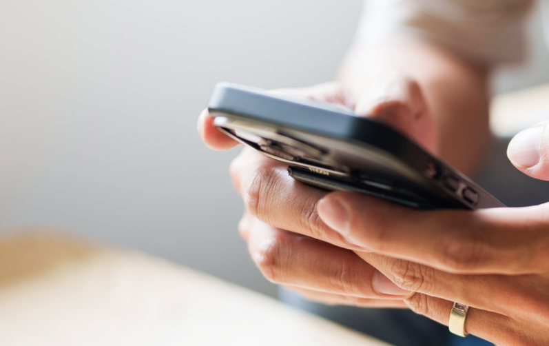 Händer som håller i mobiltelefon