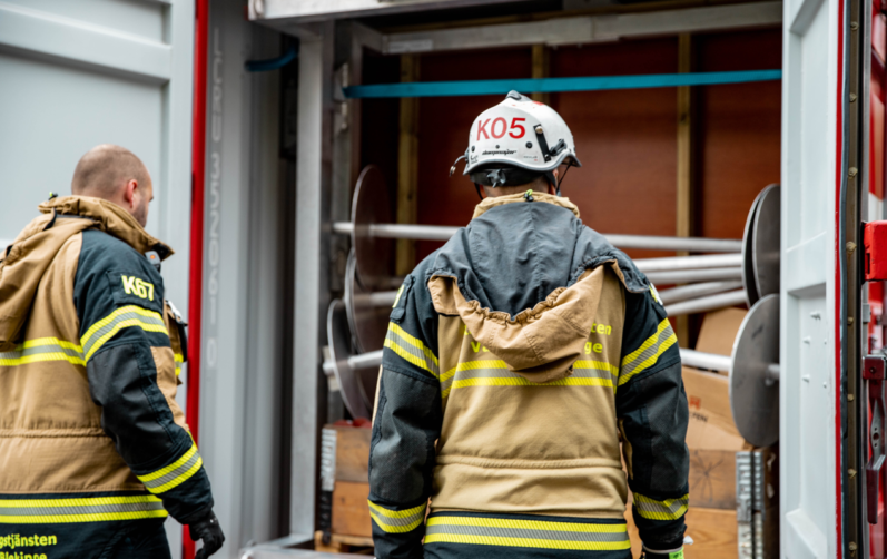 Två brandmän framför en brandbil