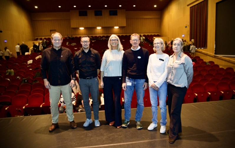 Sex personer står framför publiken.