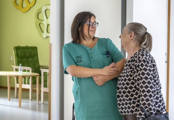 Foto på en undersköterska som står och pratar med en äldre kvinna
