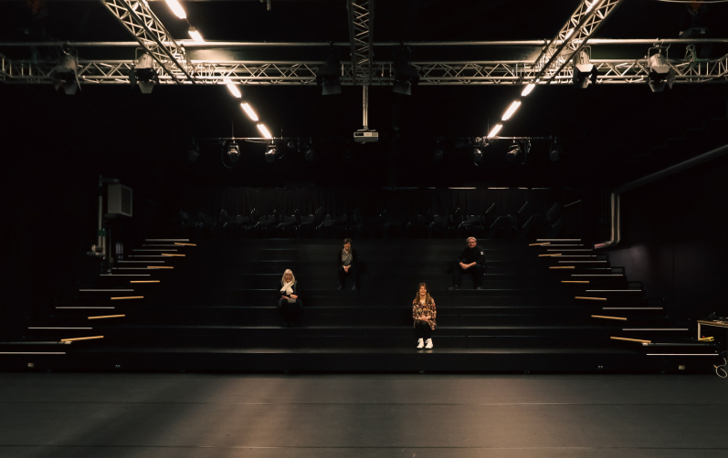 Fyra personer sitter på läktaren.